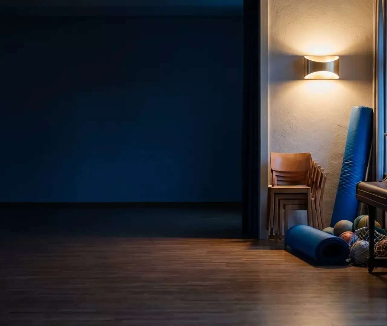 Salle communale à la tombée du jour, chaises, matériel de sport et piano rangés le long du mur, les projets soutenus par le programme MAGE Élan